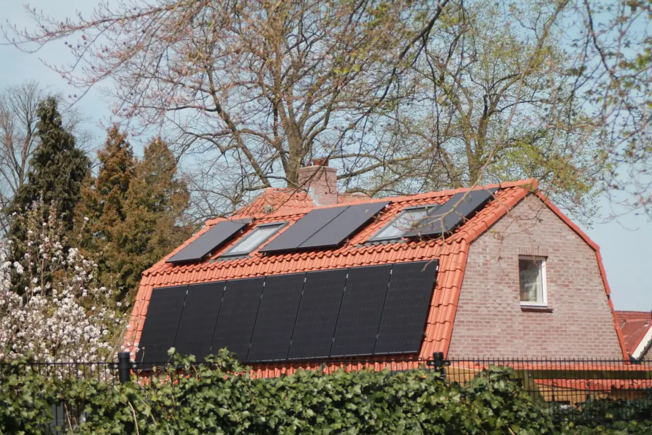 Schwarze Solarmodule und Dachfenster auf dem roten Ziegeldach eines Backsteinhauses (Tilleda, Mansfeld-Südharz)