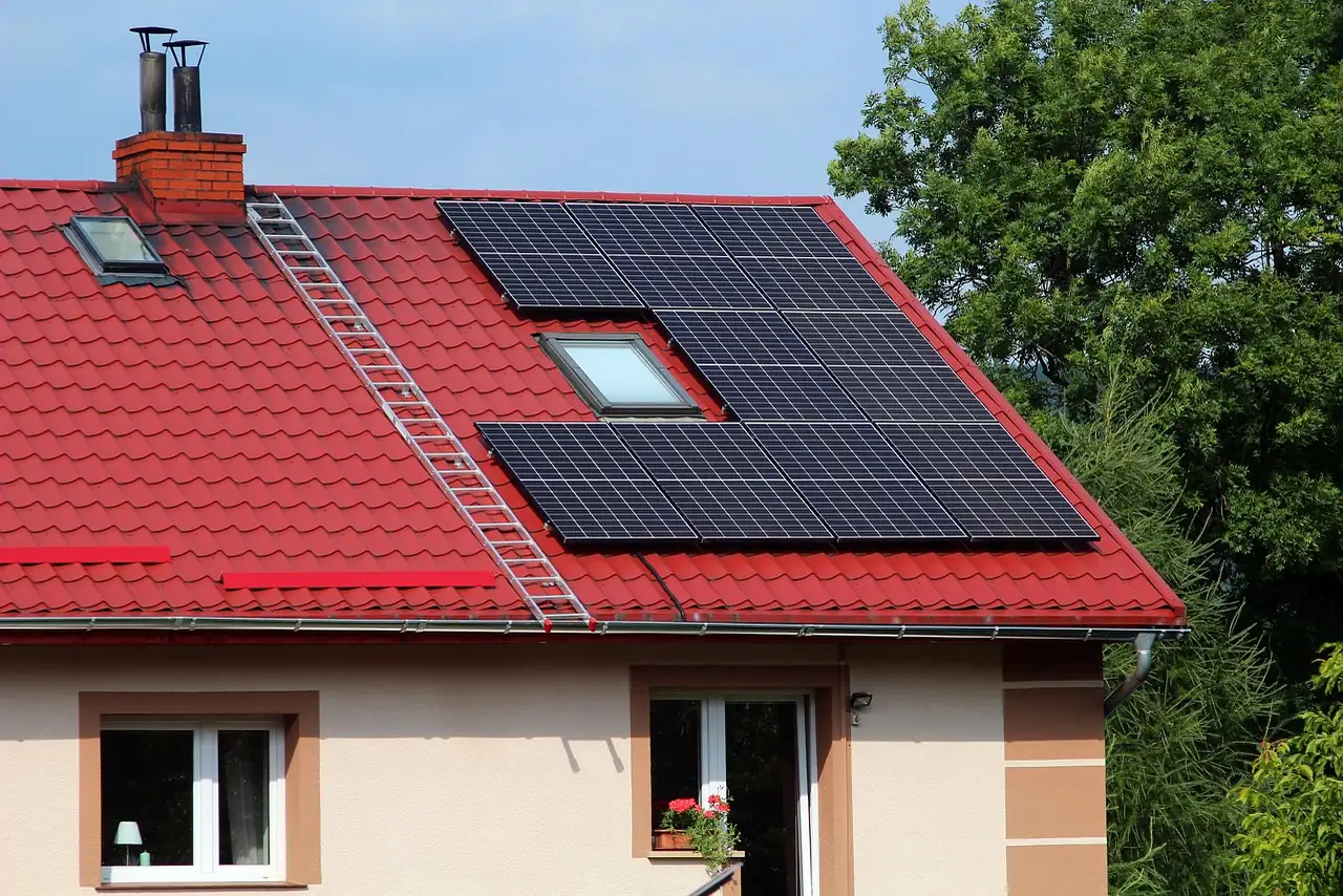 Schwarze Solarmodule, Dachfenster und Dachleiter auf dem roten Blechziegeldach eines Einfamilienhauses (Marktsteft, Landkreis Kitzingen)