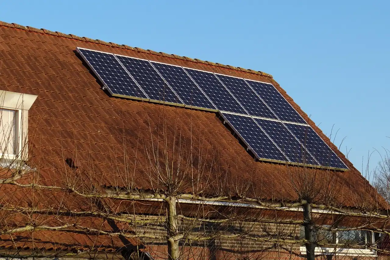 Solarmodule auf einem älteren braunroten Ziegeldach unter klarem blauem Himmel (Nübbel, Kreis Rendsburg-Eckernförde)